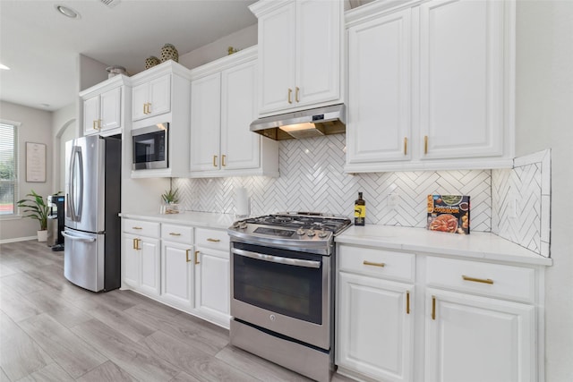4610 Western Brook Dr, Spring, TX 77388 - kitchen with appliances with stainless steel finishes, tasteful backsplash, under cabinet range hood, white cabinetry, and light wood-type flooring