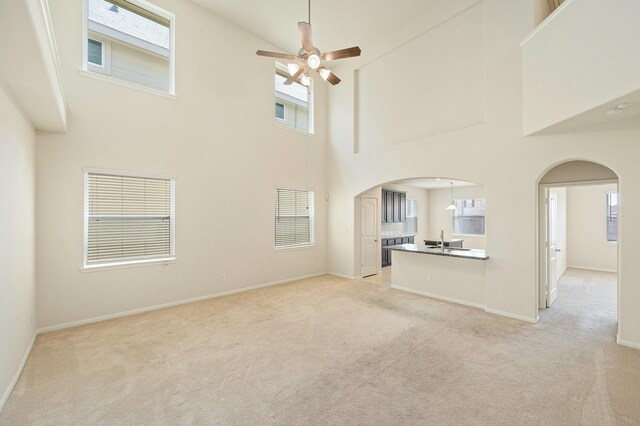 7726 Granite Terrace Ln, Houston, TX 77083 - unfurnished living room featuring arched walkways, light colored carpet, a towering ceiling, and ceiling fan