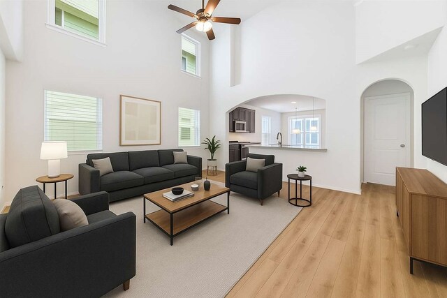 7726 Granite Terrace Ln, Houston, TX 77083 - living area featuring arched walkways, ceiling fan, light wood-style floors, and a high ceiling