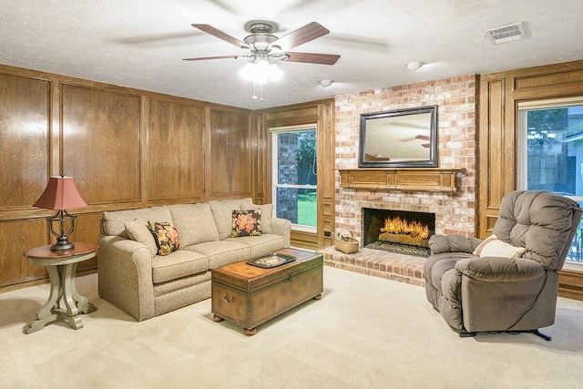 22419 Kent Falls Dr, Katy, TX 77450 - carpeted living area featuring a fireplace, a ceiling fan, a textured ceiling, and wood walls