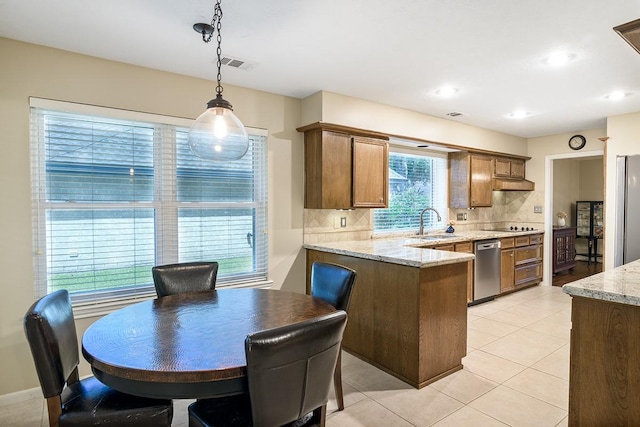 22419 Kent Falls Dr, Katy, TX 77450 - kitchen featuring a peninsula, tasteful backsplash, appliances with stainless steel finishes, hanging light fixtures, and light stone counters