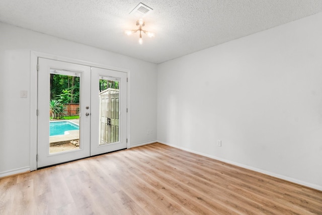 6 Fairmeade Bend Dr, The Woodlands, TX 77381 - unfurnished room featuring french doors, light wood-type flooring, and a textured ceiling