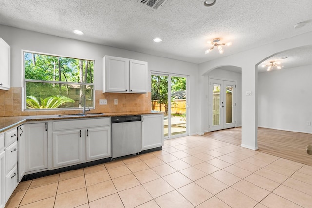6 Fairmeade Bend Dr, The Woodlands, TX 77381 - kitchen with dishwasher, backsplash, white cabinets, a textured ceiling, and arched walkways