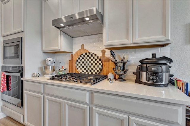 2507 Bay Breeze Dr, Kemah, TX 77565 - kitchen with extractor fan, stainless steel appliances, tasteful backsplash, and light countertops