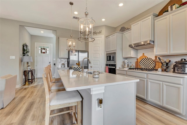 2507 Bay Breeze Dr, Kemah, TX 77565 - kitchen featuring appliances with stainless steel finishes, under cabinet range hood, decorative backsplash, a kitchen island with sink, and recessed lighting