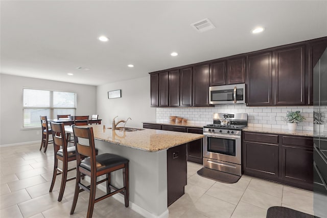 18519 Orono Ridge Trl, Richmond, TX 77407 - kitchen with appliances with stainless steel finishes, backsplash, recessed lighting, a breakfast bar, and light stone counters