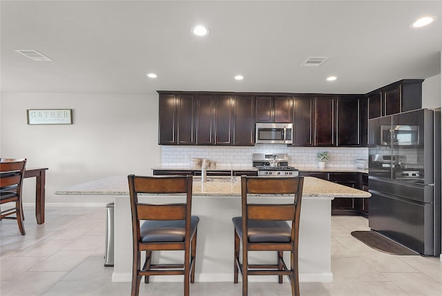 18519 Orono Ridge Trl, Richmond, TX 77407 - kitchen featuring stainless steel appliances, backsplash, light stone countertops, a kitchen island with sink, and recessed lighting