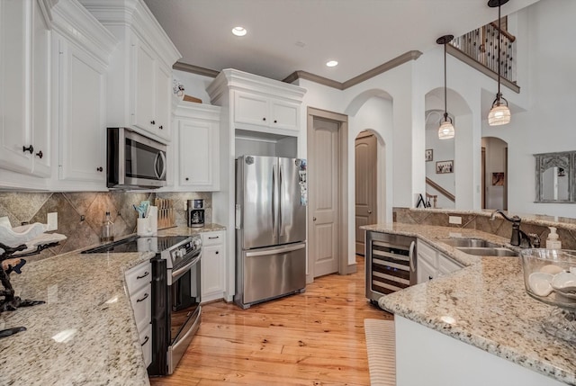4216 Karankawa Way, Jamaica Beach, TX 77554 - kitchen featuring stainless steel appliances, beverage cooler, white cabinetry, arched walkways, and light wood-type flooring