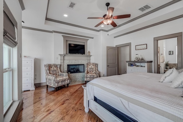 4216 Karankawa Way, Jamaica Beach, TX 77554 - bedroom featuring a fireplace, a tray ceiling, crown molding, light wood-style floors, and recessed lighting