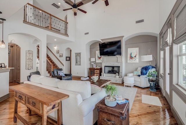 4216 Karankawa Way, Jamaica Beach, TX 77554 - living room with a ceiling fan, light wood finished floors, arched walkways, a towering ceiling, and a fireplace