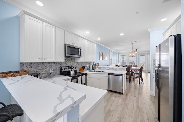 4121 Pointe W Dr Unit 301, Galveston, TX 77554 - kitchen with appliances with stainless steel finishes, a peninsula, tasteful backsplash, white cabinetry, and crown molding