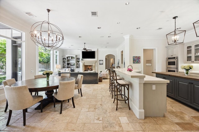 2 Hedwig Shadows Dr, Houston, TX 77024 - dining space with a chandelier, plenty of natural light, stone tile floors, ornamental molding, and a fireplace