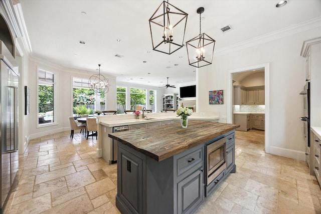 2 Hedwig Shadows Dr, Houston, TX 77024 - kitchen with a chandelier, built in appliances, a center island, stone tile floors, and wood counters