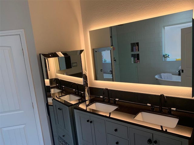8927 Alcina Dr, Tomball, TX 77375 - full bath with double vanity, a freestanding tub, and a textured ceiling