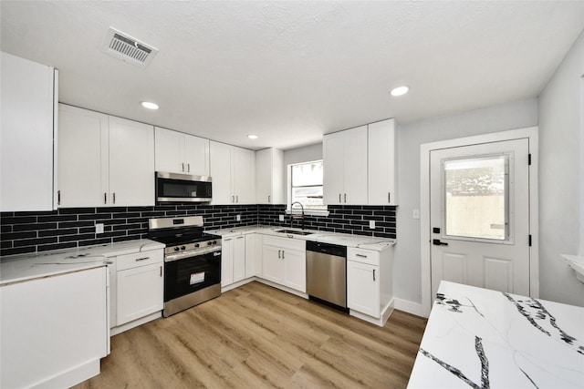 10415 Towne Oak Ln, Sugar Land, TX 77498 - kitchen featuring appliances with stainless steel finishes, light stone counters, light wood-type flooring, and recessed lighting