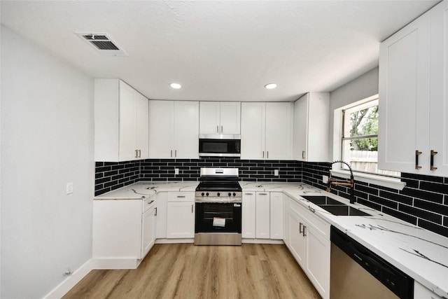 10415 Towne Oak Ln, Sugar Land, TX 77498 - kitchen featuring stainless steel appliances, light wood-style flooring, white cabinetry, backsplash, and recessed lighting