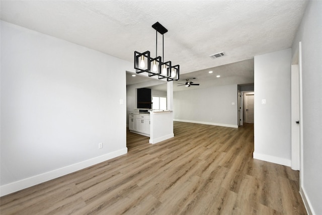 10415 Towne Oak Ln, Sugar Land, TX 77498 - unfurnished living room featuring ceiling fan, light wood-type flooring, recessed lighting, a chandelier, and a textured ceiling
