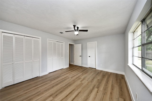 10415 Towne Oak Ln, Sugar Land, TX 77498 - unfurnished bedroom with multiple closets, wood finished floors, and a ceiling fan