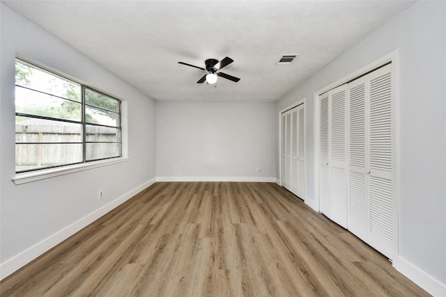 10415 Towne Oak Ln, Sugar Land, TX 77498 - unfurnished bedroom with multiple closets, light wood-style flooring, and a ceiling fan