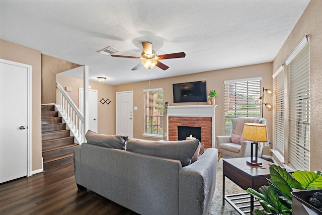 2211 S Kirkwood Rd Unit 23, Houston, TX 77077 - living room featuring ceiling fan, dark wood-style flooring, stairs, a brick fireplace, and a textured ceiling
