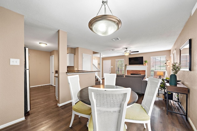 2211 S Kirkwood Rd Unit 23, Houston, TX 77077 - dining space featuring dark wood finished floors, a brick fireplace, ceiling fan, and a textured wall