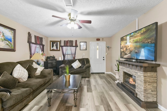 315 E Adoue St, Baytown, TX 77520 - living room featuring a textured ceiling, wood finished floors, ceiling fan, and a stone fireplace