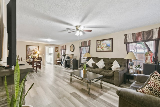 315 E Adoue St, Baytown, TX 77520 - living room featuring light wood finished floors, a ceiling fan, and a textured ceiling