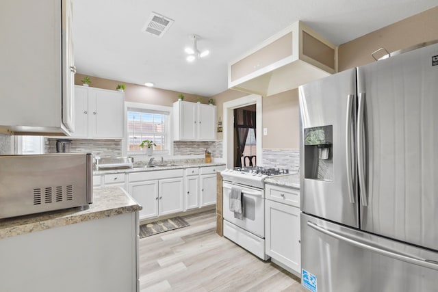 315 E Adoue St, Baytown, TX 77520 - kitchen with stainless steel refrigerator with ice dispenser, white gas stove, white cabinets, and backsplash