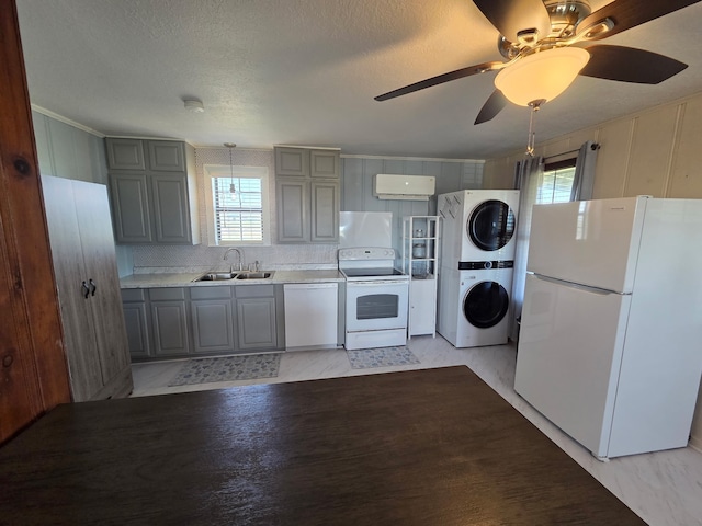 714 Caisson St, Surfside Beach, TX 77541 - kitchen with white appliances, stacked washing machine and dryer, gray cabinetry, light countertops, and ornamental molding