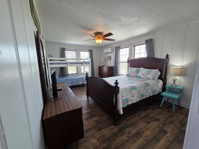 714 Caisson St, Surfside Beach, TX 77541 - bedroom featuring a decorative wall, an AC wall unit, dark wood-style floors, a textured ceiling, and a ceiling fan