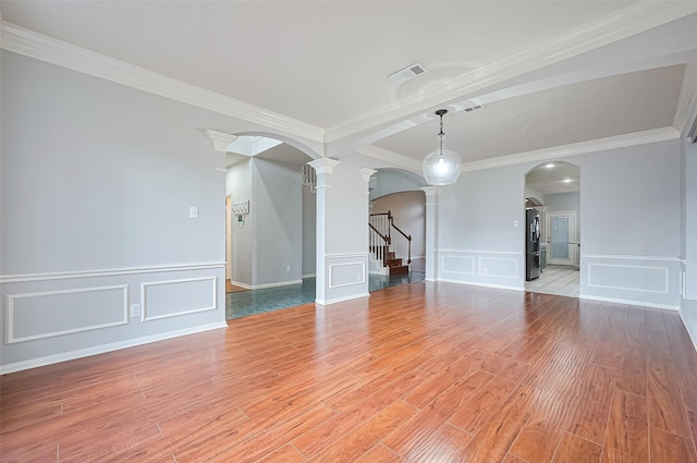 3402 Santa Catalina Ct, Katy, TX 77450 - unfurnished living room with arched walkways, decorative columns, a decorative wall, light wood-style flooring, and crown molding