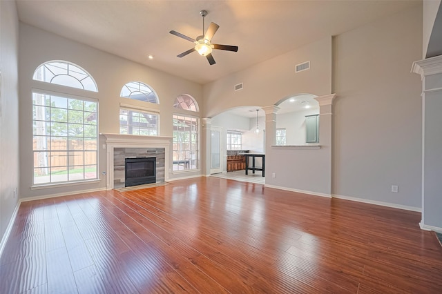 3402 Santa Catalina Ct, Katy, TX 77450 - unfurnished living room featuring decorative columns, ceiling fan, a tile fireplace, wood finished floors, and a towering ceiling
