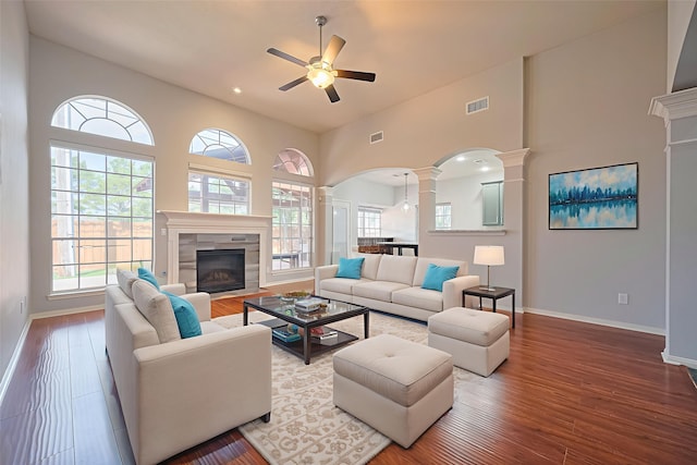 3402 Santa Catalina Ct, Katy, TX 77450 - living room with ornate columns, ceiling fan, a tiled fireplace, wood finished floors, and arched walkways