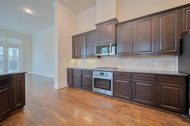 1035 E 28th St, Houston, TX 77009 - kitchen featuring stainless steel appliances, crown molding, dark brown cabinetry, and decorative backsplash