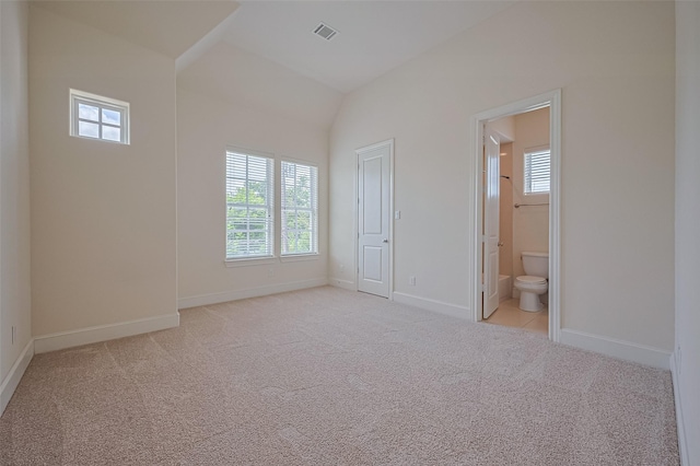 1035 E 28th St, Houston, TX 77009 - unfurnished bedroom with multiple windows, light colored carpet, lofted ceiling, and ensuite bathroom