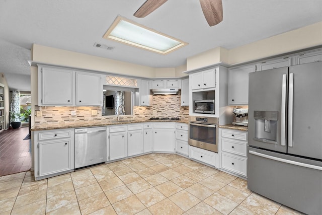 4638 Deer Point Dr, Spring, TX 77389 - kitchen featuring appliances with stainless steel finishes, tasteful backsplash, under cabinet range hood, and light stone countertops