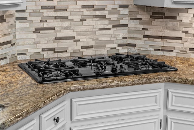 4638 Deer Point Dr, Spring, TX 77389 - kitchen view of black gas stovetop, tasteful backsplash, white cabinetry, and dark stone countertops