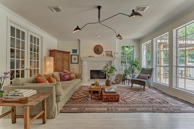 58 E Coldbrook Cir, The Woodlands, TX 77381 - living room with crown molding, a textured ceiling, a fireplace, french doors, and wood finished floors