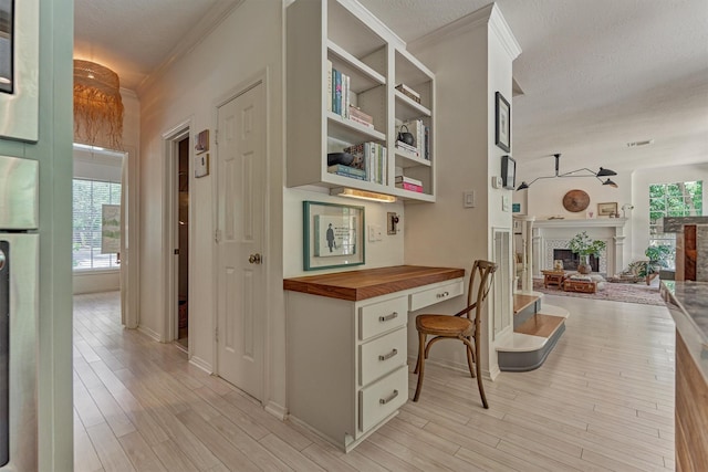 58 E Coldbrook Cir, The Woodlands, TX 77381 - corridor featuring crown molding, light wood finished floors, a textured ceiling, and a desk