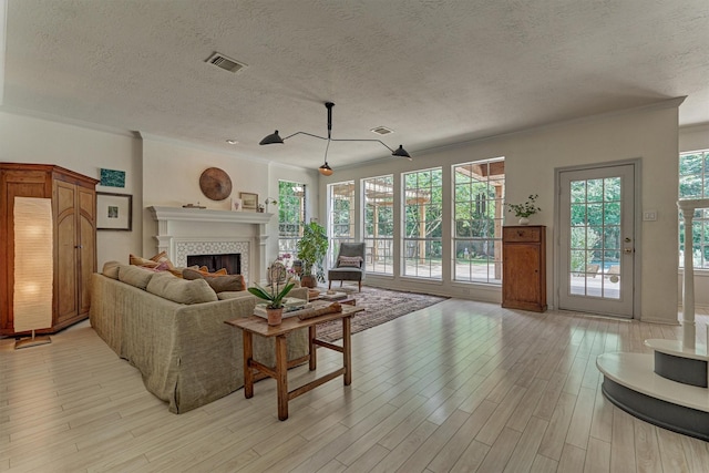 58 E Coldbrook Cir, The Woodlands, TX 77381 - living room with a textured ceiling, light wood-style flooring, a tile fireplace, and crown molding