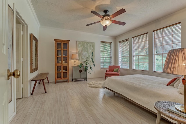 58 E Coldbrook Cir, The Woodlands, TX 77381 - bedroom featuring a textured ceiling, crown molding, light wood finished floors, and ceiling fan