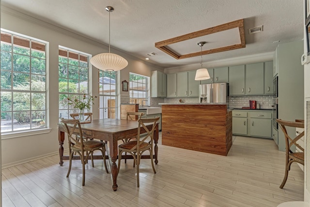 58 E Coldbrook Cir, The Woodlands, TX 77381 - dining room featuring plenty of natural light, a tray ceiling, ornamental molding, and light wood finished floors