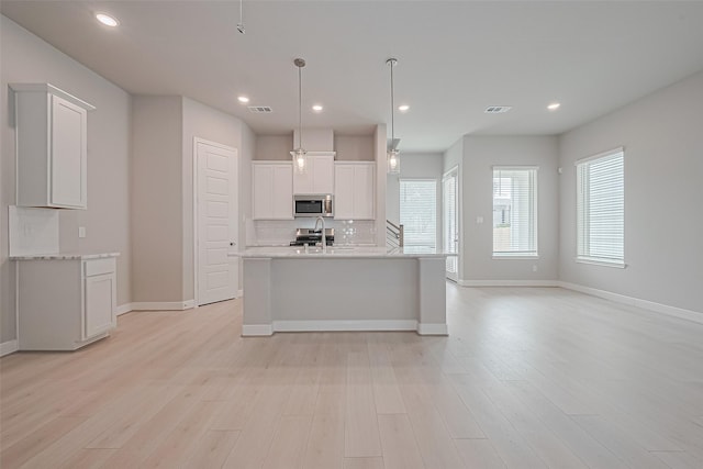 8915 Grovner Pl, Houston, TX 77055 - kitchen featuring stainless steel microwave, backsplash, white cabinetry, light wood-type flooring, and recessed lighting