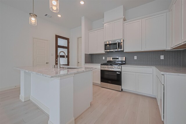 1609 Regents Gate, Houston, TX 77055 - kitchen with stainless steel appliances, light wood finished floors, decorative backsplash, a center island with sink, and recessed lighting