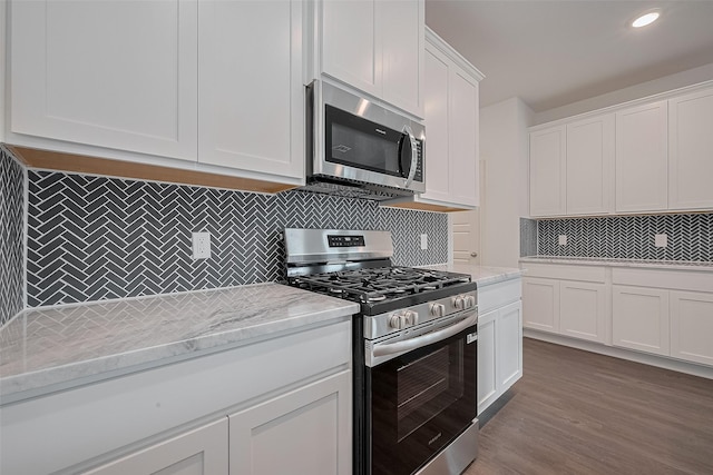 27097 Kestrel Trl, Magnolia, TX 77354 - kitchen featuring appliances with stainless steel finishes, tasteful backsplash, white cabinets, light stone countertops, and recessed lighting