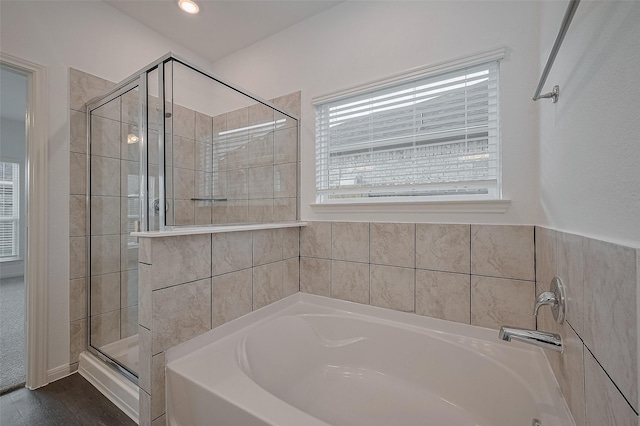 27097 Kestrel Trl, Magnolia, TX 77354 - bathroom with healthy amount of natural light, a garden tub, a stall shower, and wood finished floors