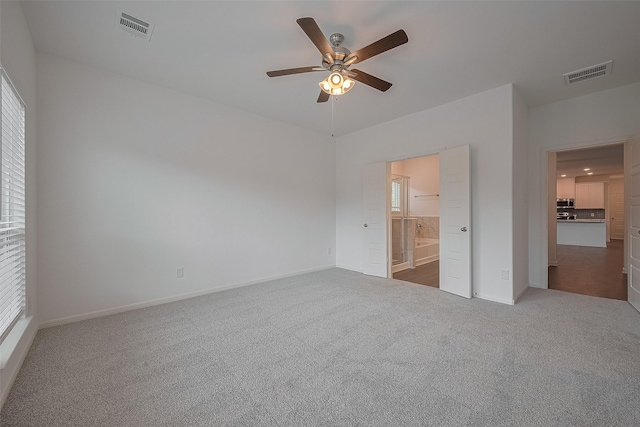27097 Kestrel Trl, Magnolia, TX 77354 - unfurnished bedroom featuring carpet flooring, multiple windows, connected bathroom, and ceiling fan