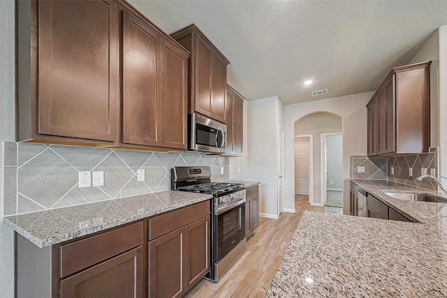 2127 Port Jackson, Texas City, TX 77568 - kitchen with stainless steel appliances, arched walkways, light wood-type flooring, light stone counters, and recessed lighting