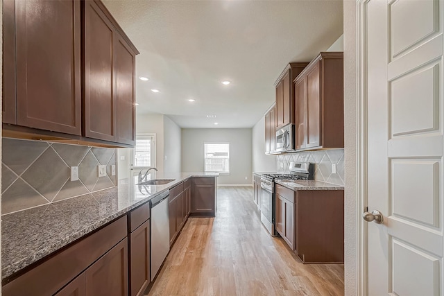 2127 Port Jackson, Texas City, TX 77568 - kitchen with stainless steel appliances, light wood-style floors, dark stone countertops, decorative backsplash, and a peninsula