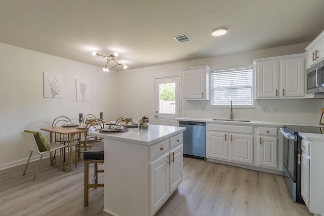 4310 Peppermint Hill Ln, Richmond, TX 77469 - kitchen with appliances with stainless steel finishes, light wood-type flooring, white cabinetry, and a kitchen island